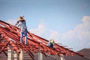 trabalhadores de solda instalando estrutura de armação de aço do telhado da casa no canteiro de obras foto