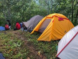 blitar, indonésia - 17 de agosto de 2022 barracas de acampamento e algumas pessoas conversando e curtindo no topo da montanha pela manhã foto