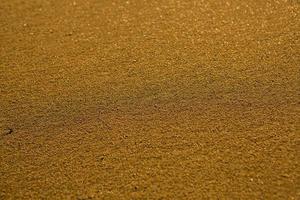 fundo com areia dourada na costa da ilha de creta. superfície abstrata com areia e água do mar clara para texto. foto