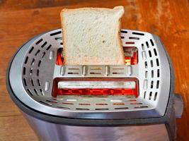 fatia de pão fresca na torradeira de metal quente foto
