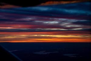 crepúsculo à noite do avião a jato ver o céu azul laranja vermelho com a luz da cidade da tailândia abaixo foto