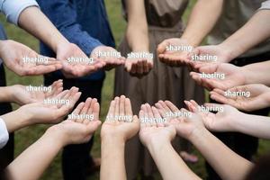 homens e mulheres asiáticos levantam a mão direita e, em seguida, mantêm o texto compartilhando juntos no grupo de círculo no jardim. foto