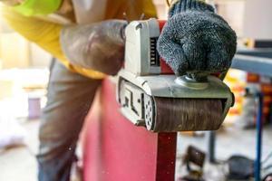 carpinteiro está raspando a porta de madeira vermelha por sua máquina de barbear em campo ao ar livre com ambiente de estrutura de construção de poste de aço. foto