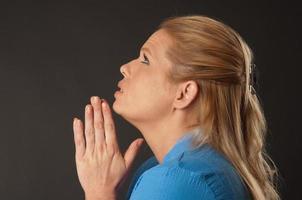 Vista lateral da mulher loira rezando