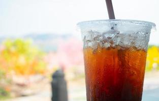 café americano com cubos de gelo em um copo de plástico transparente. bebidas geladas populares em cafés, atrações turísticas, durante o dia, quando o clima está quente. foto