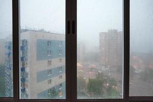 gotas de chuva na janela da casa urbana durante a chuva foto