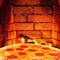 pizza com salame e parede de tijolo quente do forno foto
