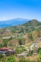 colinas verdes com aldeias e etna na sicília foto