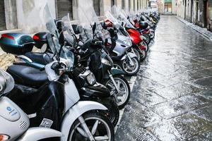 muitas scooters molhadas estacionadas na rua em florença foto