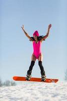 jovem e bela mulher pulando em uma prancha de snowboard foto