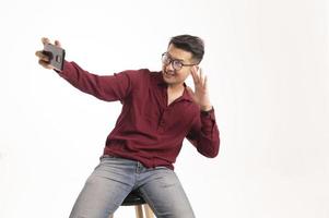 homem asiático inteligente usando smartphone no fundo do estúdio, bonito jovem asiático sorrindo alegremente na camisa formal. usando um smartphone para trocar ou conversar foto