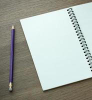 caderno espiral em branco e lápis sobre fundo escuro de madeira foto