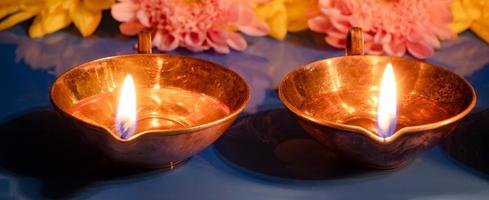 feliz Diwali. queimando lâmpadas de óleo diya e flores sobre fundo azul. tradicional festival indiano de luz. foto