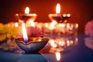 feliz Diwali. símbolos tradicionais do festival indiano de luz. queimando lâmpadas de óleo diya e flores sobre fundo vermelho. foto