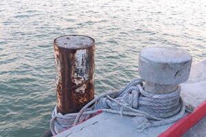 pilar de aço no mar é amarrado com um poste de concreto com uma corda foto