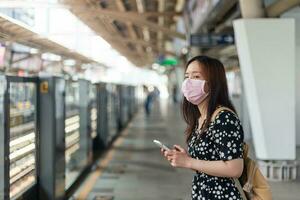 passageiro jovem mulher asiática esperando o trem do metrô com a cidade no fundo do dia com espaço de cópia. foto