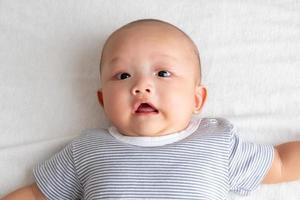 um bebê em uma camisa listrada está chocado no tapete branco. foto