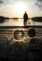 um pôr do sol calmo em um lago com um par de óculos de sol em primeiro plano foto