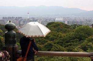 mulher com guarda-chuva olhando sobre kyoto, japão, do castelo de kyoto foto