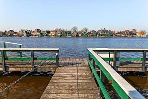 cidade de amsterdã à beira do rio com casas coloridas e porto de madeira, reportagem de viagem foto