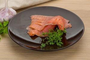 fatias de salmão no prato e fundo de madeira foto