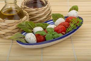 salada caprese em uma tigela com fundo de madeira foto