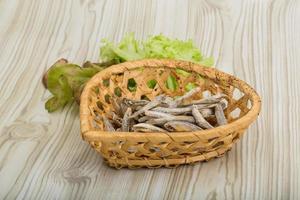 seca a anchova em uma cesta no fundo de madeira foto