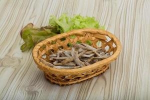 seca a anchova em uma cesta no fundo de madeira foto