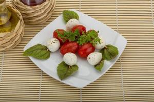 salada caprese no prato e fundo de madeira foto