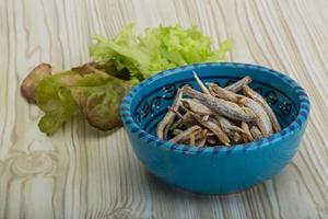 seca a anchova em uma tigela sobre fundo de madeira foto