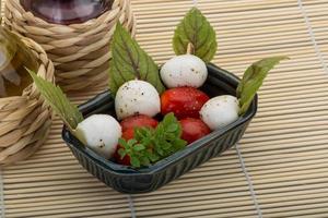 salada caprese em uma tigela com fundo de madeira foto