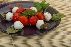 salada caprese no prato e fundo de madeira foto