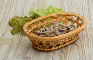 seca a anchova em uma cesta no fundo de madeira foto