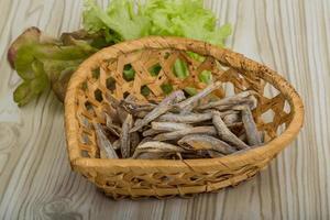 seca a anchova em uma cesta no fundo de madeira foto