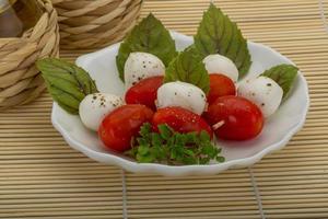 salada caprese no prato e fundo de madeira foto