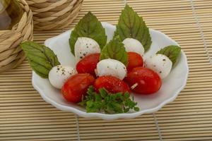 salada caprese no prato e fundo de madeira foto