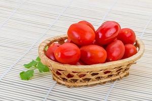 tomate cereja em uma cesta em fundo de madeira foto