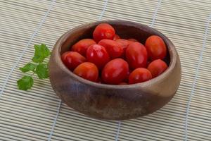 tomate cereja em uma tigela sobre fundo de madeira foto