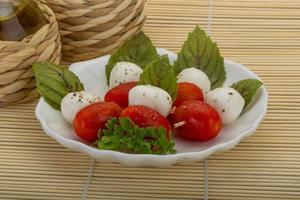 salada caprese no prato e fundo de madeira foto