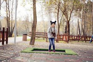 menina da escola feliz pulando em um pequeno trampolim no parque foto