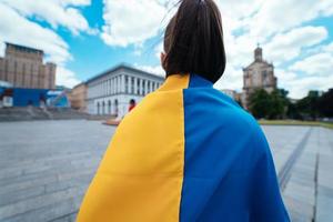 vista traseira. jovem coberta com a bandeira ucraniana foto