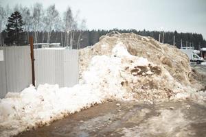 cerca está coberta de neve. removeu a neve para o lado da estrada. foto