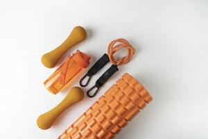 diferentes equipamentos coloridos para exercícios de fitness e esporte halteres e expansores laranja, bolas de fitness e bandas deitadas sobre um fundo branco foto
