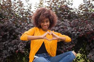 uma mulher afro-americana feliz e jovem mostra um coração com as mãos foto