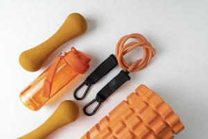 diferentes equipamentos coloridos para exercícios de fitness e esporte halteres e expansores laranja, bolas de fitness e bandas deitadas sobre um fundo branco foto