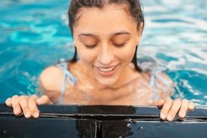 jovem descansando na beira da piscina foto