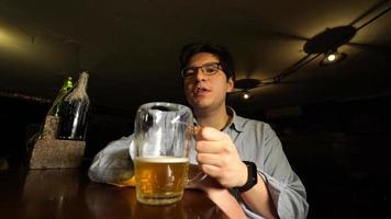 cara bebendo cerveja e conversando com a câmera no bar à noite foto