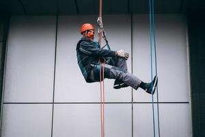 alpinista industrial em uniforme e capacete sobe foto