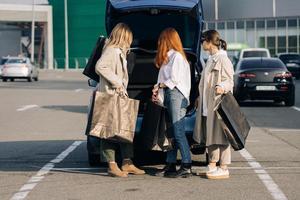 mulheres jovens no carro com sacolas de compras foto