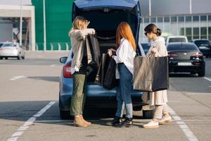 mulheres jovens no carro com sacolas de compras foto